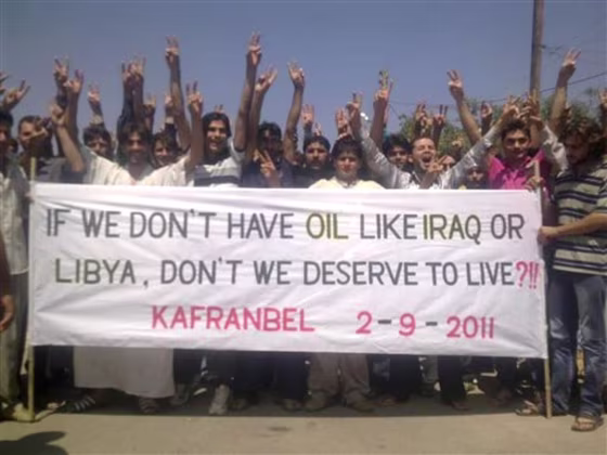 In this citizen journalism image taken on a cellphone and provided by Shaam News Network, protesters hold a banner during a demonstration against the Syrian regime at Kfar Nebel village, in Edlib province, Syria, on Friday.